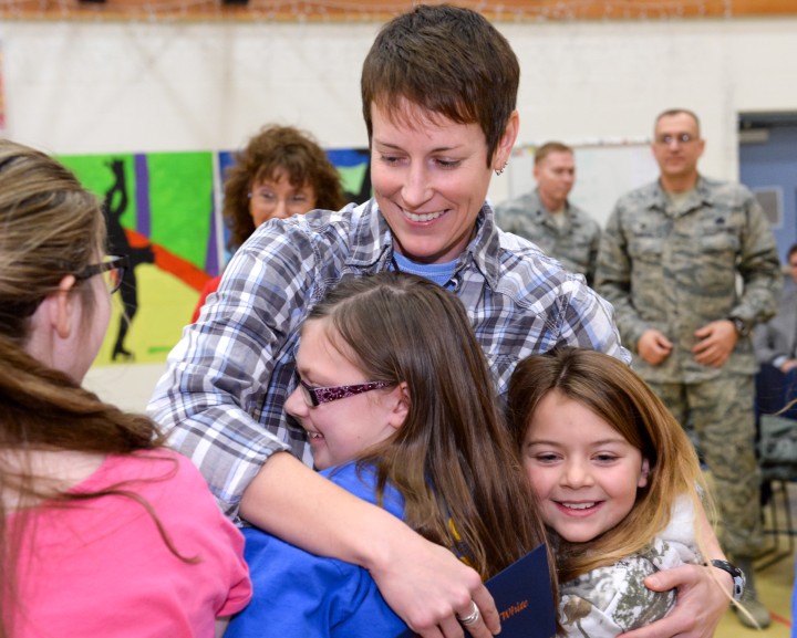 Jenna White hugged by children w soldiers