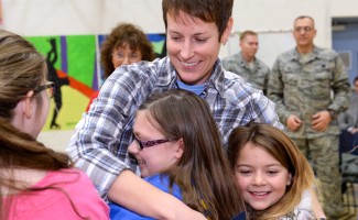 Jenna White hugged by children w soldiers