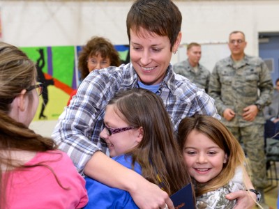 Jenna White hugged by children w soldiers